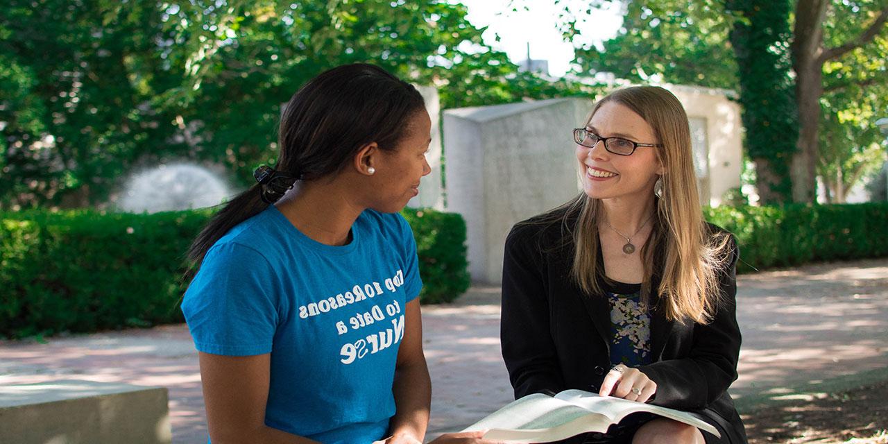 UE faculty and student talking outside